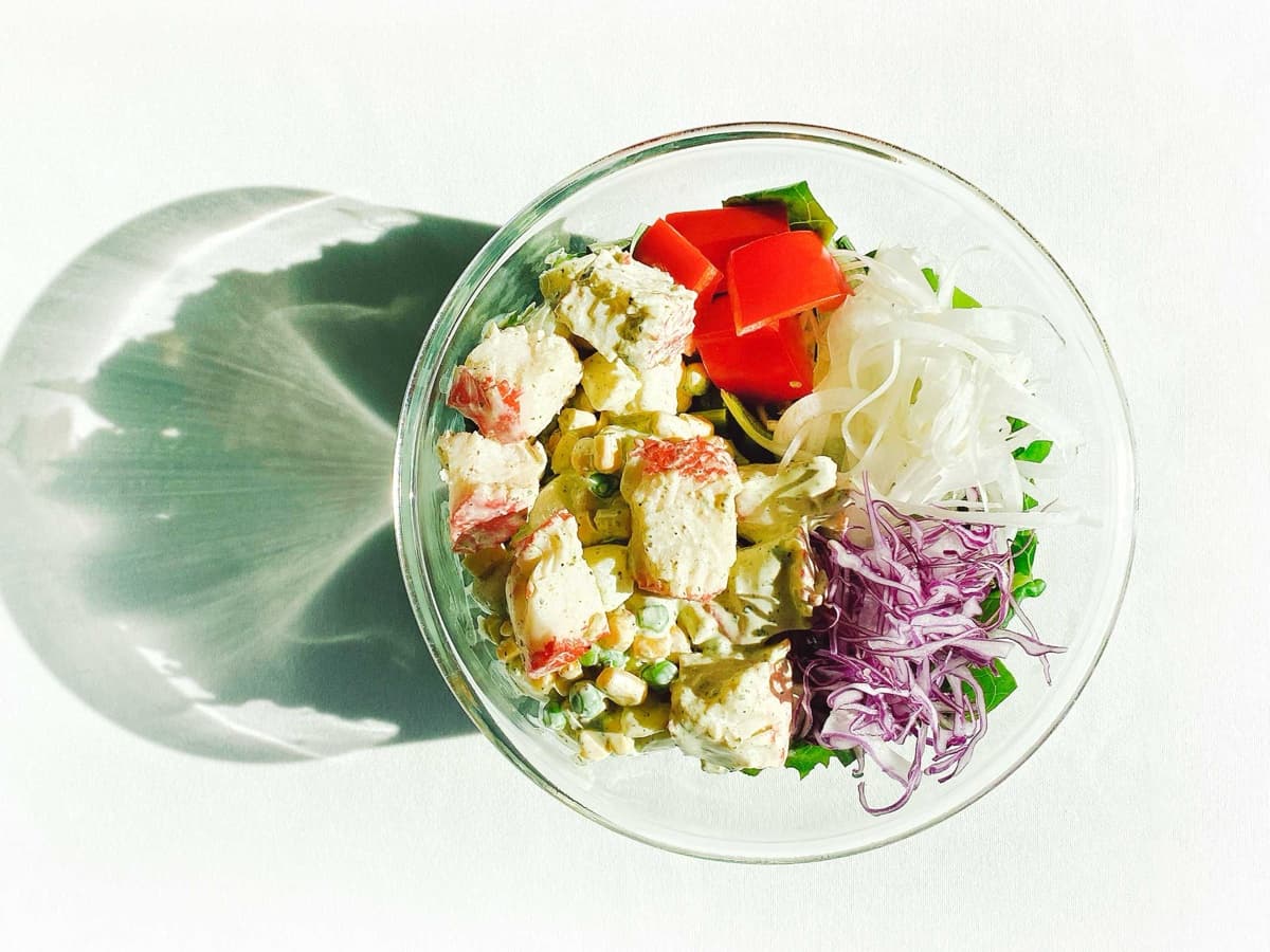 투명 볼에 담긴 샐러드밀. 꽃맛살, 감자, 완두콩, 파프리카, 적양배추, 양파, 잎채소가 담겨 있다